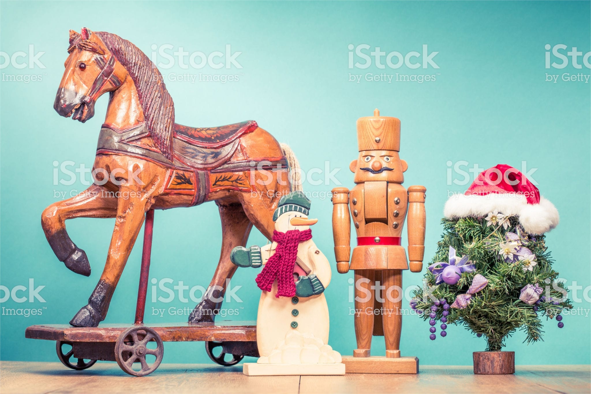 Retro antique Christmas wooden horse on wheels toy, old snowman, nutcracker and New Year tree in Santa's hat. Holiday greeting card. Vintage style filtered photo