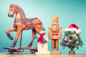 Retro antique Christmas wooden horse on wheels toy, old snowman, nutcracker and New Year tree in Santa's hat. Holiday greeting card. Vintage style filtered photo